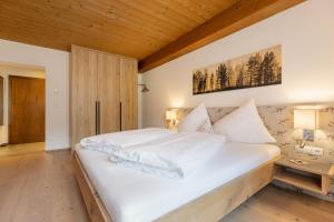 a bedroom with a white bed with a wooden ceiling at Hotel Garni Jagdhof in Zell am Ziller