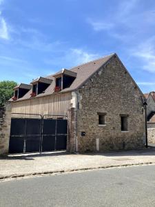 La Cour Verte : Chaleureuse grange réhabilitée في Montépilloy: مبنى من الطوب كبير مع بابين كبيرين لوقوف السيارات