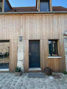 een houten huis met een blauwe deur en twee ramen bij La Cour Verte : Chaleureuse grange réhabilitée in Montépilloy
