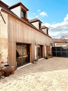 La Cour Verte : Chaleureuse grange réhabilitée في Montépilloy: مبنى مع ساحة مع نافذة كبيرة
