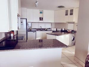Una cocina con gabinetes blancos y encimeras de granito. en 15 Dorado Bay, en Tinley Manor 10 fotos más