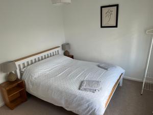 a bedroom with a white bed with a wooden frame at Spacious one bed apartment in a quiet leafy close. in Barnstaple