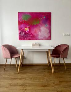 einen Tisch und zwei Stühle vor einem Gemälde in der Unterkunft Art Apartment Telč in Telč
