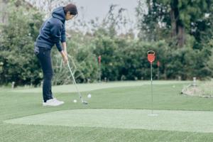 una mujer jugando golf en un putting green en Ryokute -OHTAKI- - Vacation STAY 22904v, en Ōtaki