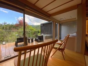 um quarto com uma varanda com uma mesa e uma grande janela em Kaiseki Ryokan Ashikari em Yugawara
