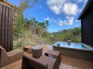 a patio with a hot tub and chairs at Kaiseki Ryokan Ashikari in Yugawara