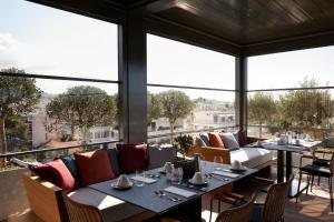 een restaurant met tafels en stoelen en grote ramen bij Dusit Suites Athens in Athene