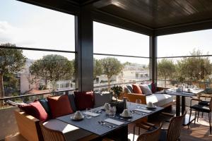Dusit Suites Athens في أثينا: مطعم بطاولات وكراسي ونوافذ كبيرة
