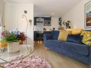 uma sala de estar com um sofá azul e uma mesa de vidro em The Sunflower em Windermere