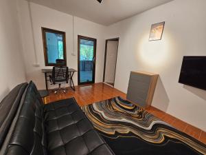 uma sala de estar com um sofá, uma televisão e uma secretária em Village Home, 1br+1lr em Ban Madua Wan