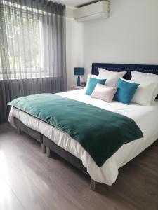 1 dormitorio con 1 cama grande con almohadas azules y blancas en Aux Couleurs d'Alsace en Ostwald