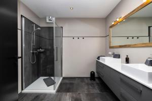 a bathroom with a shower and two sinks and a mirror at Landhaus Rustika in Wagrain