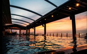 a swimming pool with a sunset in the background at Dyne Oceano Hotel in Jeju