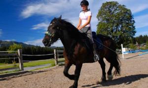 eine Frau, die auf einem Pferd auf einer unbefestigten Straße reitet in der Unterkunft Deluxe Apartment DONNA in Schladming