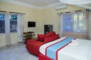 a bedroom with a large bed and a red couch at Jacyjoka Apartments Nyali in Mombasa