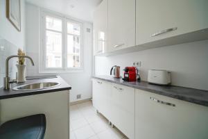 Una cocina con gabinetes blancos y un fregadero y una ventana. en Apartment next to Palais des Congrès - Neuilly, en Neuilly-sur-Seine 14 fotos más