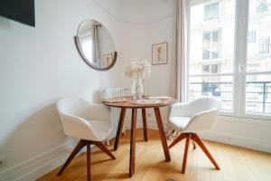 mesa de comedor con 2 sillas blancas y espejo en Apartment next to Palais des Congrès - Neuilly en Neuilly-sur-Seine