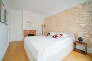 1 dormitorio con cama blanca y pared en Apartment next to Palais des Congrès - Neuilly en Neuilly-sur-Seine