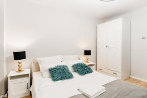 Dormitorio blanco con cama blanca y almohadas verdes en Beautiful and cozy 2 bedroom apartment with living room loft en Cluj-Napoca