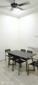 une table et des chaises noires avec un ventilateur de plafond dans l'établissement RW segamat homestay, à Segamat