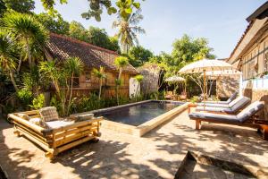 una piscina con 2 sillas y una sombrilla en Ardi Beltza Hotel and Private Pool Villa en Gili Air