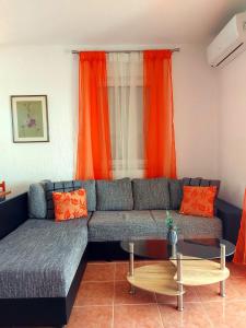 een woonkamer met een blauwe bank en oranje gordijnen bij Panorama Pakoštane in Pakoštane