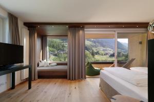 ein Schlafzimmer mit einem großen Fenster mit einem Bett und einem TV in der Unterkunft Alpine Life Hotel Anabel in Steinhaus