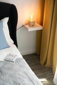 a bed with a book and a candle on a side table at Letnica living space apartment in Gdańsk