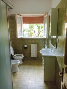 uma casa de banho com um WC, um lavatório e uma janela em appartamento con giardino vicino al mare em Palidoro
