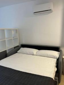 um quarto com uma cama com lençóis brancos e uma ventoinha em Entremares estudio a 150 metros playa em Roquetas de Mar