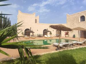 a house with a swimming pool with chairs and umbrellas at Riad Bini-Ddik in Essaouira