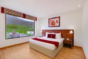 a bedroom with a bed and a large window at Lemon Tree Hotel Manali in Manāli