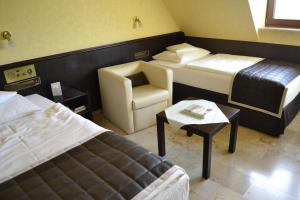 a hotel room with two beds and a chair at Flair Park Hotel Ilshofen in Ilshofen