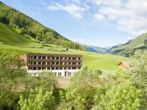 un bâtiment dans un champ avec des montagnes en arrière-plan dans l'établissement Alpine Life Hotel Anabel, à Cadipietra