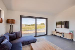 ein Wohnzimmer mit einem blauen Sofa und einem Fernseher in der Unterkunft Villa neuve avec piscine vue sur mer pour 9 in Pléneuf-Val-André