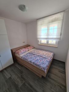 a small bedroom with a bed and a window at Apartman Ivana in Porat