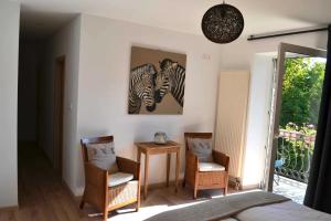 ein Schlafzimmer mit 2 Stühlen und einem Bild von Zebras in der Unterkunft Aux Gîtes de l'Étang - Thannenkirch Bergheim in Thannenkirch