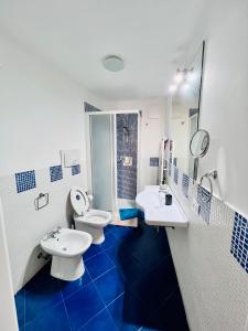 a blue and white bathroom with two sinks and a toilet at B&B Vivaldi in Palermo