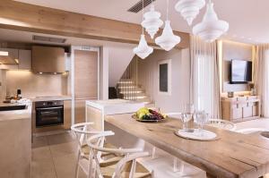 - une cuisine avec une table en bois et des chaises blanches dans l'établissement Villa Kalloni, à Siteía