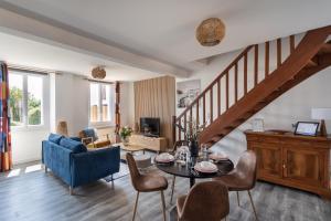 un soggiorno con tavolo, sedie e scala di La Maison de Louise - Superbe maison avec patio a Cancale
