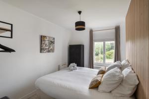 una camera da letto con un letto bianco con cuscini e una finestra di La Maison de Louise - Superbe maison avec patio a Cancale