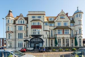 a large building with cars parked in a parking lot at Cliftonville Hotel in Cromer