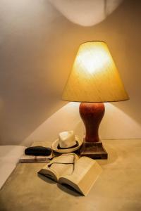 une lampe assise sur une table avec un livre et un chapeau dans l'établissement Margossa Residence by 55TG, à Kandy