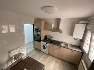 a kitchen with a sink and a washing machine at Casa Raquelina in Gijón