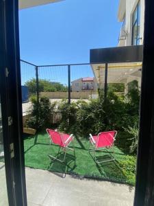 - deux chaises roses assises sur l'herbe sur un balcon dans l'établissement Seaside retreat. two room apartment. quiet area, à Năvodari
