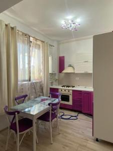 une cuisine avec des placards violets et une table avec des chaises dans l'établissement Seaside retreat. two room apartment. quiet area, à Năvodari