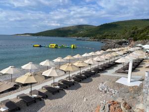 einen Strand mit Sonnenschirmen und einem Floß im Wasser in der Unterkunft Lustica Bay - Centrale 1 Bed Apartment in Tivat