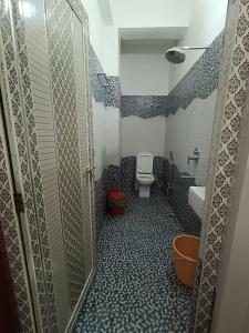 a small bathroom with a toilet and a shower at Saraswati Palace in Varanasi