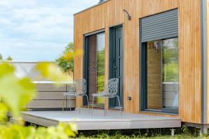 ein winziges Haus mit zwei Stühlen auf einer Terrasse in der Unterkunft Le Laponya - Chalet climatisé avec SPA & Borne de recharge in Bressols