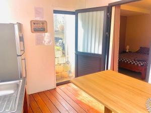 a kitchen with a refrigerator and a table and a door at Le MélanZé in Grande Anse